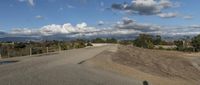 an empty road stretches into the distance with hills in the background and a mountain in the distance