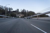 the back end of a car is driving down an empty road near a large archway