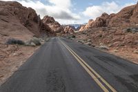 an empty road in the desert with no people on it and a yellow line painted down the middle