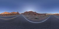 an empty road with cars on both sides with mountains in the distance and blue sky