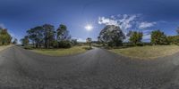 a fisheye view of an empty road with some trees on either side of it