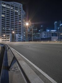 an empty road at night in an urban area that is mostly empty, with skyscrapers in the background