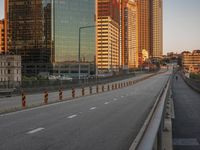 the empty road is lined with orange striped tape as the sun sets over the city skyline