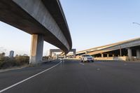 a car driving by an overpass on an empty road in a city with high rise bridge