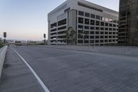 an empty road and parking lot on a sunny day at dusk with skyscrapers in the distance