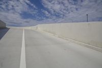 there is a long empty road in this area with blue skies in the background and white concrete along the side of the road