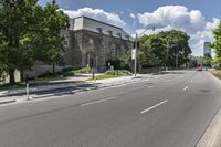 an empty road and residential building on a clear day of summer in the city with trees