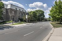 an empty road and residential building on a clear day of summer in the city with trees