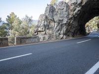 an empty road goes into a rock cave as it is closed to traffic and people walk