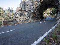 an empty road goes into a rock cave as it is closed to traffic and people walk