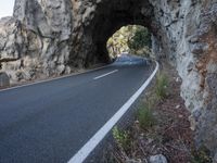 an empty road goes into a rock cave as it is closed to traffic and people walk