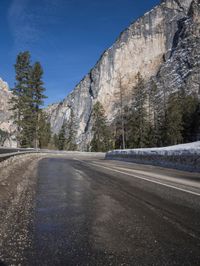 an empty road is lined with rocks along the edge of the valley and snowy mountain in the distance