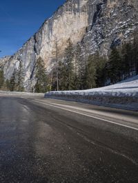 an empty road is lined with rocks along the edge of the valley and snowy mountain in the distance