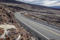 an empty road through the rocky outcropping and arid mountain landscape below it