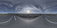 a fish eye lens with an empty road going up the sides of it and some clouds above