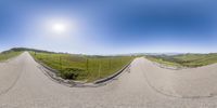 the wide view of an empty road in a rural field is seen through the perspective mirror