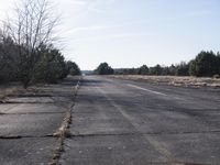 a empty road with trees in the distance on the side of it as people walk by