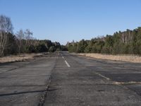 a empty road with trees in the distance on the side of it as people walk by