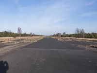a empty road with trees in the distance on the side of it as people walk by