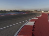 an empty track with some traffic in the distance and some clouds in the sky behind it