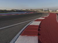 an empty track with some traffic in the distance and some clouds in the sky behind it