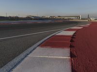 an empty track with some traffic in the distance and some clouds in the sky behind it