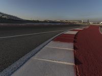 an empty track with some traffic in the distance and some clouds in the sky behind it