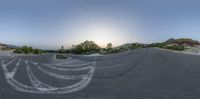 a fisheye lens view of an empty road with trees and grass in the background