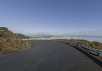 an empty road with a fog filled area on both sides of it and mountains in the distance