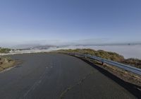 an empty road with a fog filled area on both sides of it and mountains in the distance