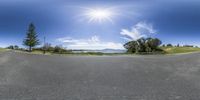 this is an empty road with the sun in the background and the blue sky above