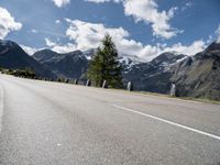 the motorcycle is on the empty road beside the mountains and a snow - capped mountain