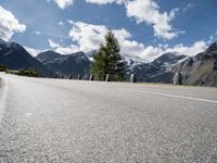 the motorcycle is on the empty road beside the mountains and a snow - capped mountain