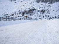 an empty road and snow covered mountains near the tracks in the distance are train tracks
