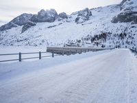 an empty road and snow covered mountains near the tracks in the distance are train tracks