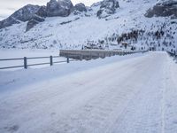 an empty road and snow covered mountains near the tracks in the distance are train tracks