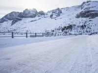 an empty road and snow covered mountains near the tracks in the distance are train tracks