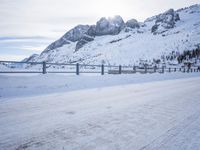 an empty road and snow covered mountains near the tracks in the distance are train tracks