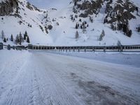 an empty road and snow covered mountains near the tracks in the distance are train tracks