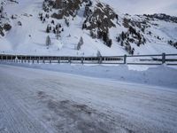 an empty road and snow covered mountains near the tracks in the distance are train tracks
