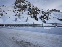 an empty road and snow covered mountains near the tracks in the distance are train tracks
