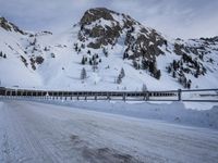 an empty road and snow covered mountains near the tracks in the distance are train tracks