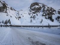 an empty road and snow covered mountains near the tracks in the distance are train tracks