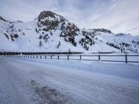 an empty road and snow covered mountains near the tracks in the distance are train tracks