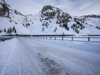 an empty road and snow covered mountains near the tracks in the distance are train tracks