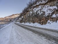 an empty road and snowy mountains at dusk or day time during winter season with a dustin of snow