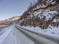 an empty road and snowy mountains at dusk or day time during winter season with a dustin of snow