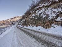 an empty road and snowy mountains at dusk or day time during winter season with a dustin of snow