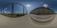 a panoramic photo of power lines next to an empty road and a building in the distance