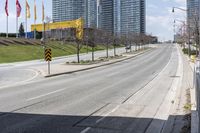 an empty road with some buildings and flags on the sidewalk nearby it are also in the distance